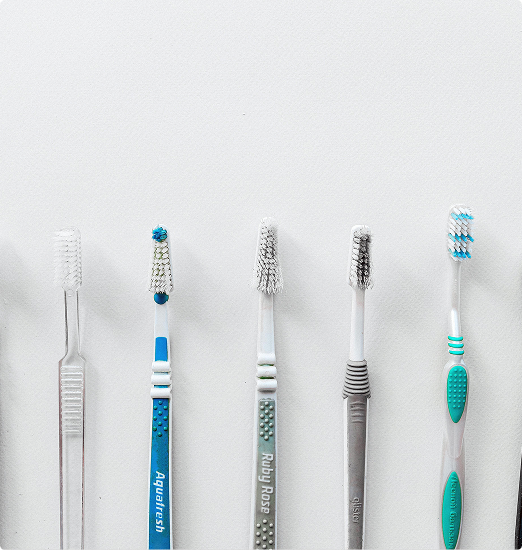 A lineup of six toothbrushes with various designs and colors, including blue, aqua, and grey, against a plain white background.